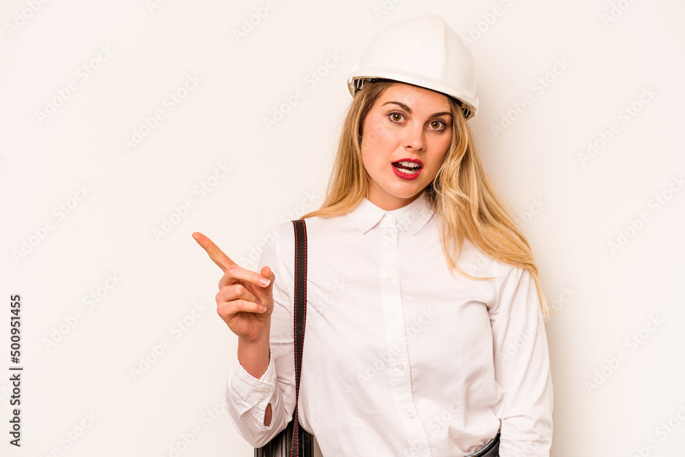 Young architect woman with helmet and holding blueprints isolated on white background pointing to the side Young architect woman with helmet and holding blueprints isolated on white background pointing to the side