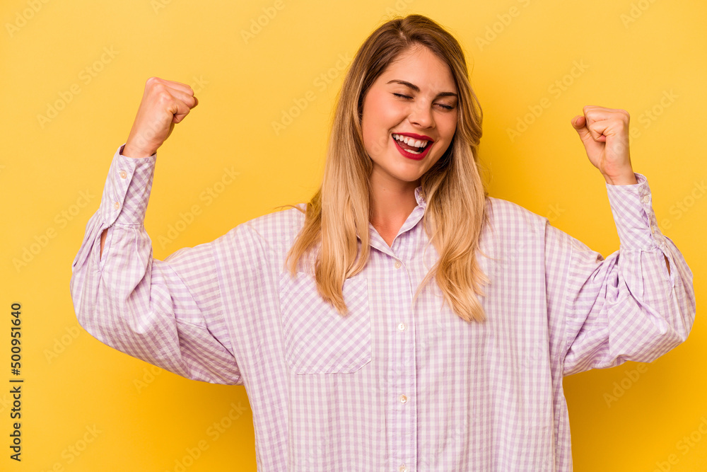 Young caucasian woman isolated on yellow background raising fist after a victory, winner concept.