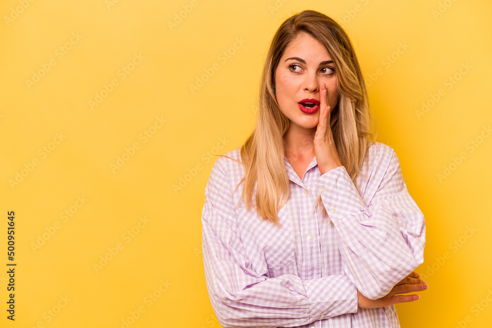 Young caucasian woman isolated on yellow background is saying a secret hot braking news and looking aside Young caucasian woman isolated on yellow background is saying a secret hot braking news and looking aside