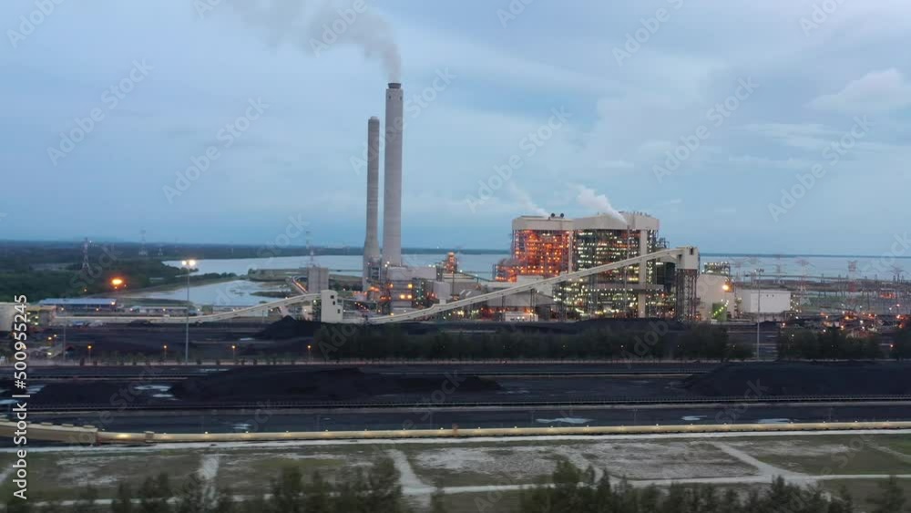 Tracking shot across industrial ultra-supercritical coal-fired power plant with smokes raising from chimney by Tenaga Nasional Berhad TNB located at Manjung, Perak, Malaysia at dusk. Tracking shot across industrial ultra-supercritical coal-fired power plant with smokes raising from chimney by Tenaga Nasional Berhad TNB located at Manjung, Perak, Malaysia at dusk.