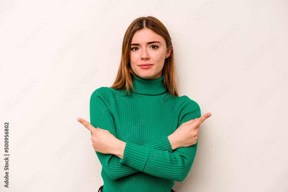 Young caucasian woman isolated on white background points sideways, is trying to choose between two options. Young caucasian woman isolated on white background points sideways, is trying to choose between two options.