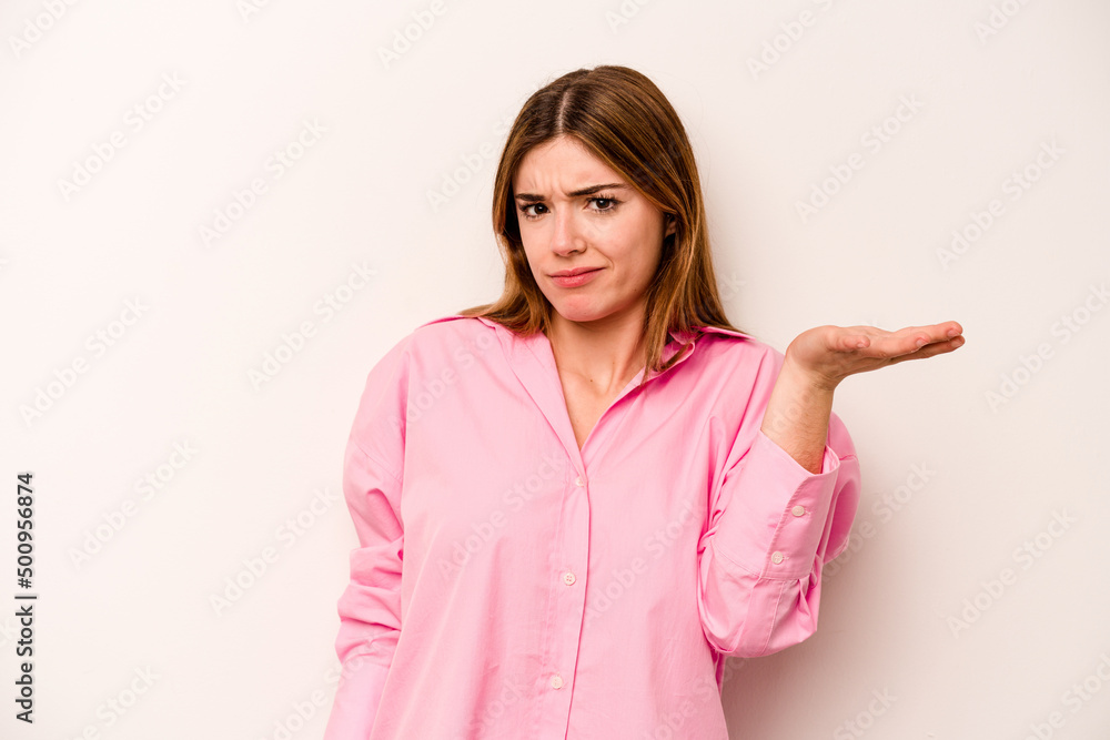 Young caucasian woman isolated on white background doubting and shrugging shoulders in questioning gesture. Young caucasian woman isolated on white background doubting and shrugging shoulders in questioning gesture.