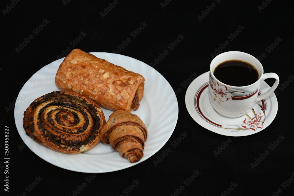 porcelain platter with Croissants, and a cup of coffee on black background porcelain platter with Croissants, and a cup of coffee on black background