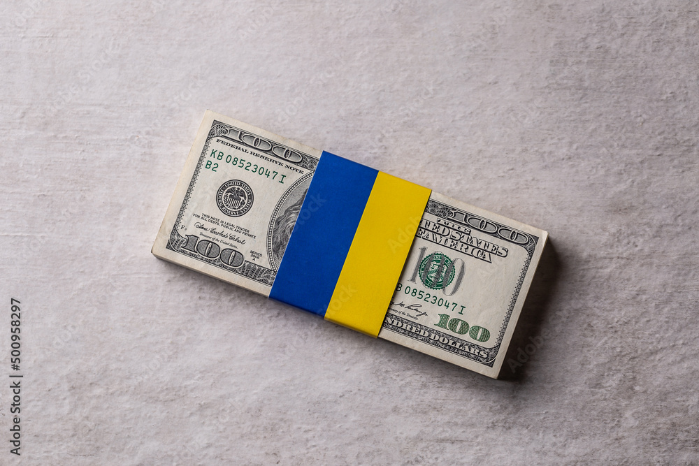 Bundles of dollar bills tied with the Ukrainian flag. The concept of support of the American government, for the war-torn Bundles of dollar bills tied with the Ukrainian flag. The concept of support of the American government, for the war-torn