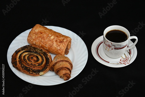 porcelain platter with Croissants  and a cup of coffee on black background
