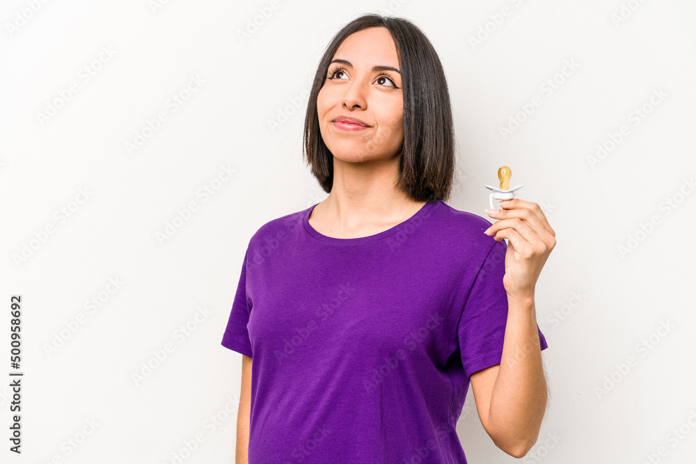 Young hispanic pregnant woman holding pacifier isolated on white background dreaming of achieving goals and purposes
