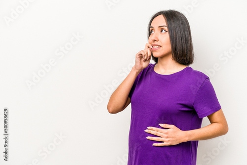 Young hispanic pregnant woman isolated on white background relaxed thinking about something looking at a copy space.