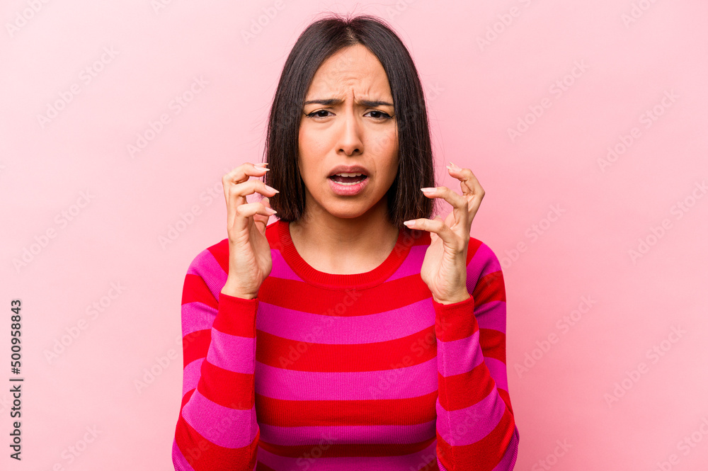Young hispanic woman isolated on pink background upset screaming with tense hands. Young hispanic woman isolated on pink background upset screaming with tense hands.