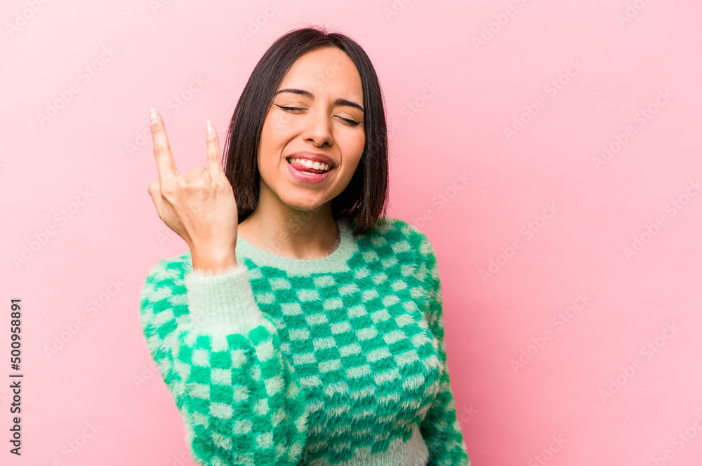 Young hispanic woman isolated on pink background showing rock gesture with fingers Young hispanic woman isolated on pink background showing rock gesture with fingers