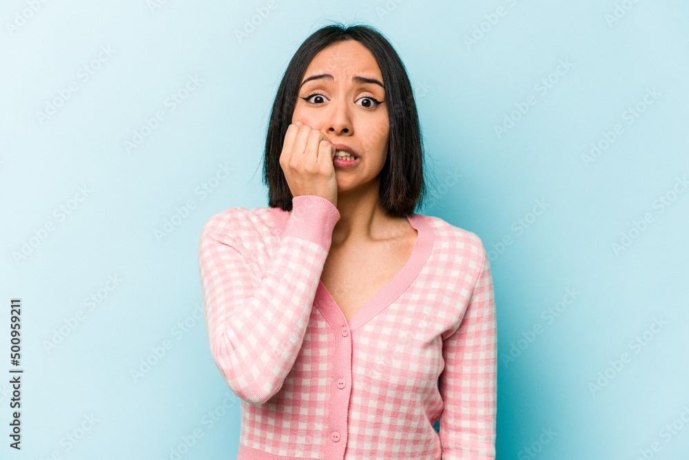 Young hispanic woman isolated on blue background biting fingernails, nervous and very anxious. Young hispanic woman isolated on blue background biting fingernails, nervous and very anxious.