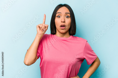 Young hispanic woman isolated on blue background having an idea, inspiration concept.