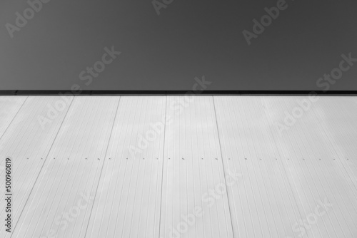 Commercial warehouse aluminium wall and roof against sky. Black and white