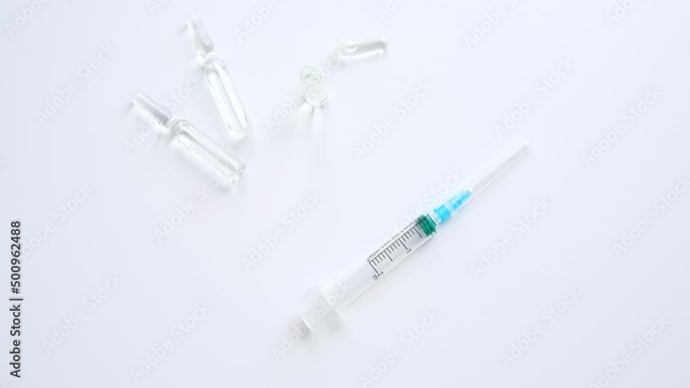 Medical syringe and ampoules with clear liquid on a white background. 4K footage Medical syringe and ampoules with clear liquid on a white background. 4K footage