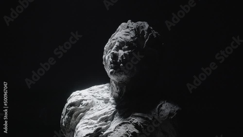 A white statue of a man. A close-up shot on a black background.
