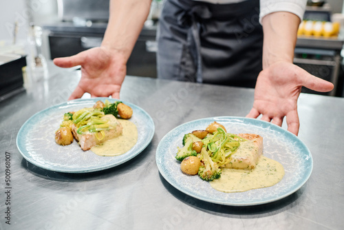 Close-up of chef putting plates with ready dish on kitchen counter for delivery