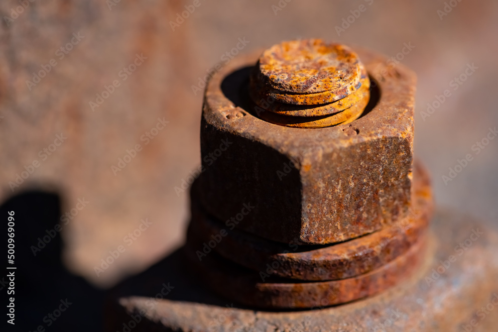 Rusty corroded iron screw with washer and thread vertical on a railway profile. Monochrome orange brown metal surface of a hex nut fixing. Macro close up with selective focus. Rusty corroded iron screw with washer and thread vertical on a railway profile. Monochrome orange brown metal surface of a hex nut fixing. Macro close up with selective focus.