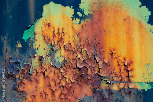 Peeled off paint on rusty vehicle surface of a ruined train. Vintage metal background with wheathered rotten color and massive corrosion in shades and gradients of orange, yellow, green, blue, brown photo