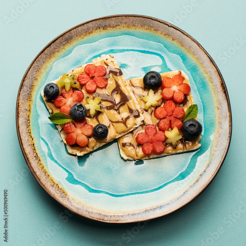 Sweet sandwiches peanut butter with fruits, berries with honey on a plate, top view. Healthy tasty breakfast.