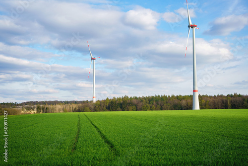 Panoramic view of wind farm or wind park on sunny day, with high wind turbines for generation electricity with copy space. Green energy concept.