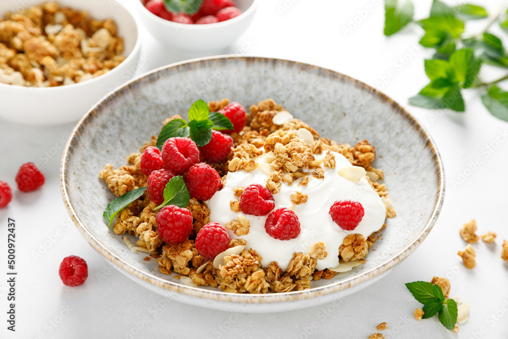 Granola with white plain yogurt and fresh raspberry in a bowl, healthy food for breakfast Granola with white plain yogurt and fresh raspberry in a bowl, healthy food for breakfast