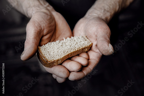 Dirty hands homeless old poor man with piece of bread, top view. Concept global crisis, economic recession