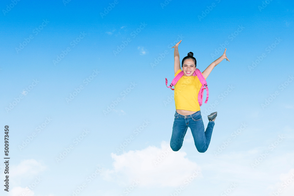Happy female student jumping on blue sky Happy female student jumping on blue sky