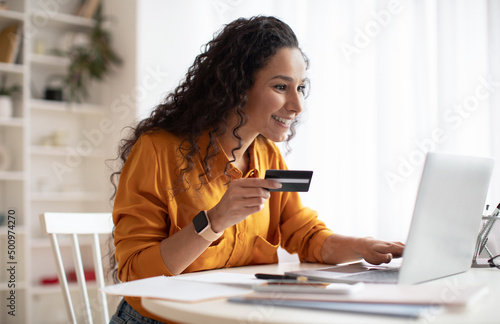 Businesswoman Shopping Online Using Credit Card And Laptop At Workplace photo