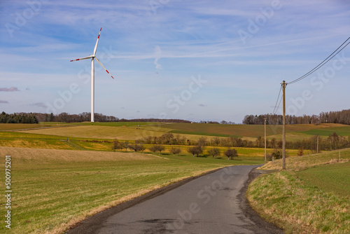A single wind turbine and a power line on the countryside