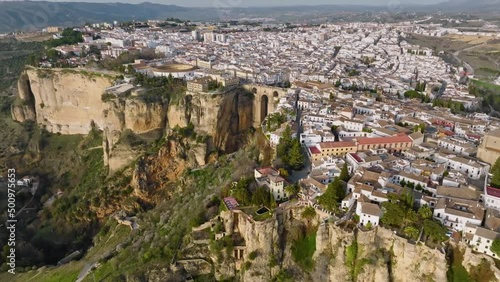 Flying over Ronda and Puente Nuevo Bridge. Aerial view of houses and cathedral in Ronda, Andalusia, Spain