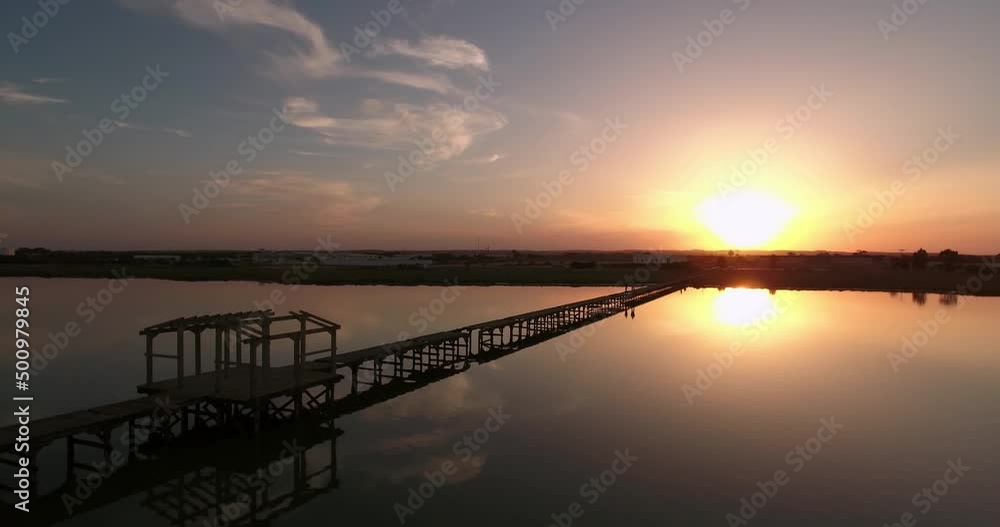 Aerial Panning Shot Of Tourists Walking On Jetty During Sunset, Drone Flying Backwards Over Lake - Djerba, Tunisia Aerial Panning Shot Of Tourists Walking On Jetty During Sunset, Drone Flying Backwards Over Lake - Djerba, Tunisia