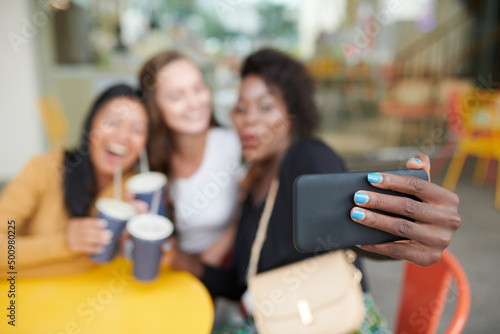 Woman with bright blue nail polish taking selfie with best friends in cafe  selective focus