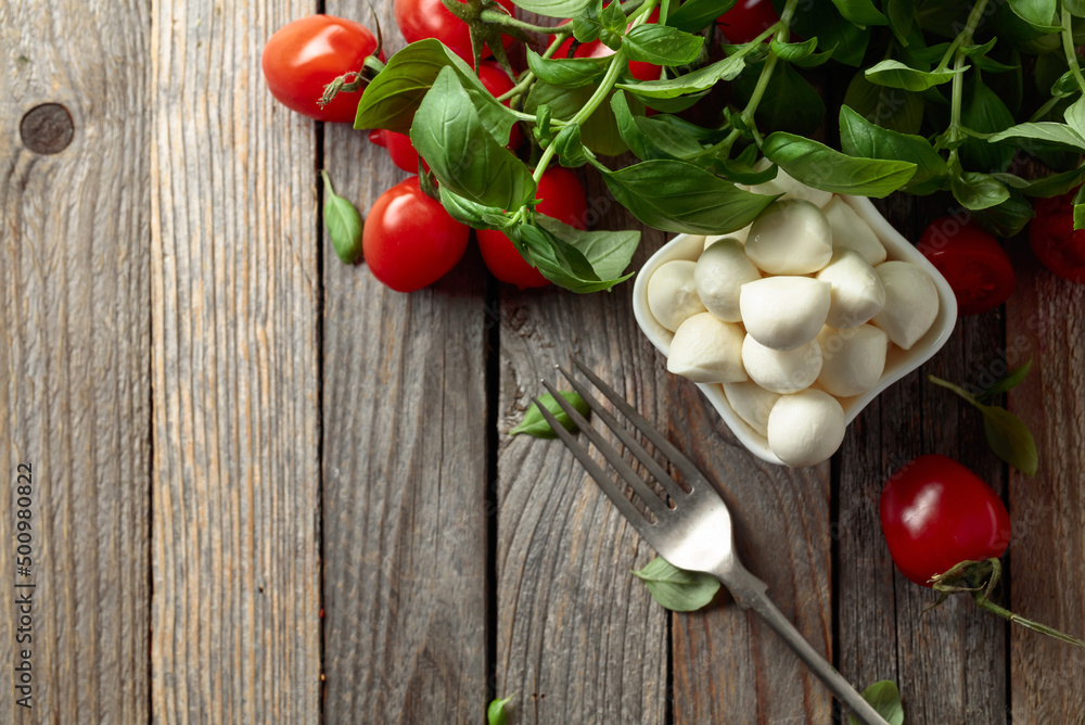 Mozzarella cheese with basil and tomatoes on an old wooden table. Mozzarella cheese with basil and tomatoes on an old wooden table.