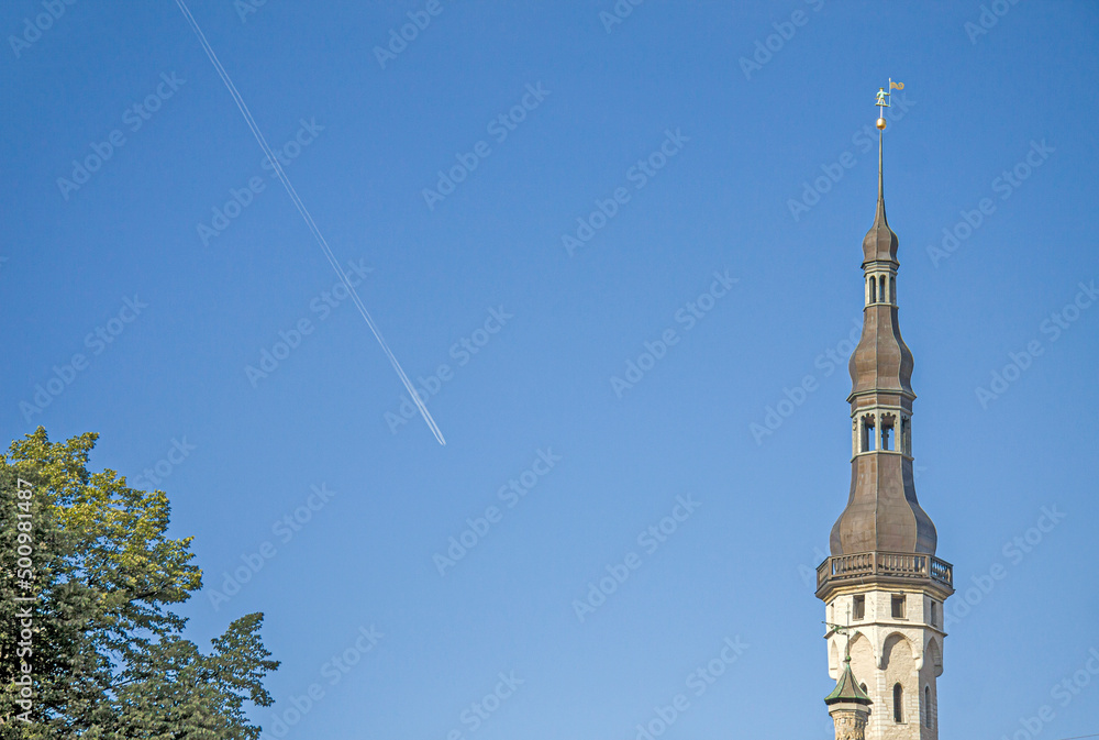 Obraz premium Old town hall tower and jet contrail. Tallinn, Estonia