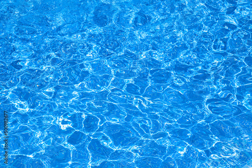 Background, water waves in the pool with sun reflection