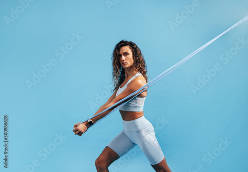 Murais de parede Strong and fit woman doing intense training with resistance band