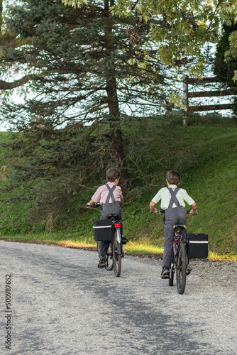 Two Amish boys riding their bikes on a country road   Holmes County  Ohio