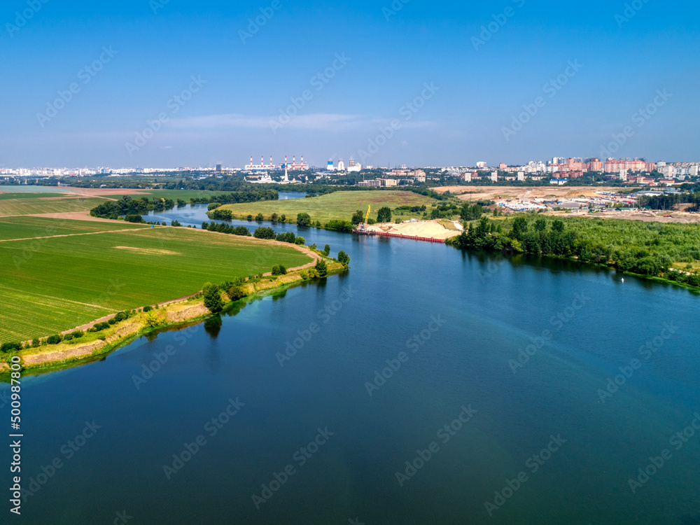 Wide river flowing between fields Wide river flowing between fields