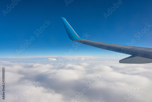 Wing view of the airplane on a winglets, stratus clouds on the skyline during climbing flight level.