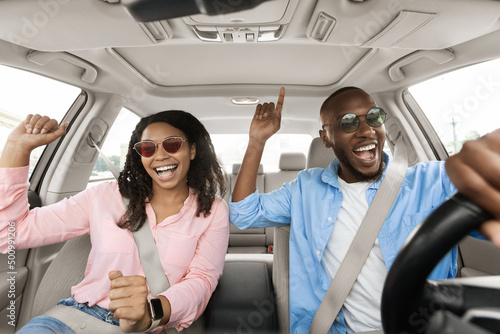 Fotografie, Obraz Happy black couple enjoying music driving luxury car
