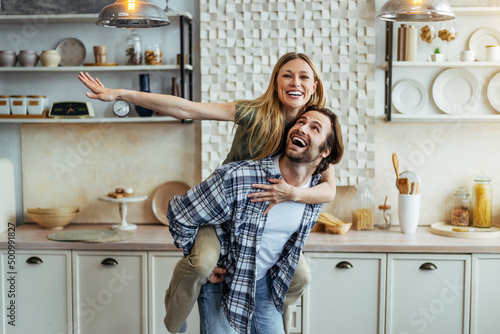Billede på lærred Happy young european guy rolls his wife on back and have fun together in modern