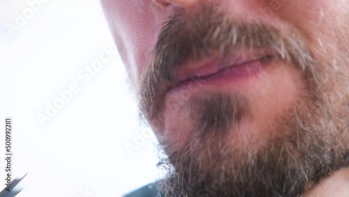 Close-up portrait of young guy puts pickled mushroom in mouth and chews with pleasure. Man eats wild mushrooms.