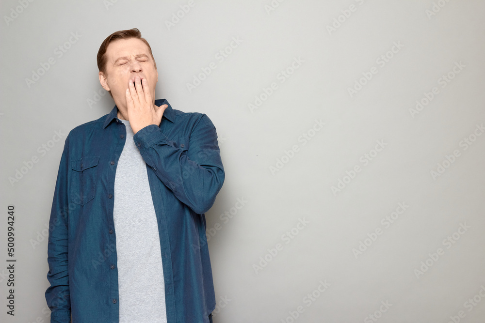 Portrait of mature man yawning at large, covering mouth with hand Portrait of mature man yawning at large, covering mouth with hand