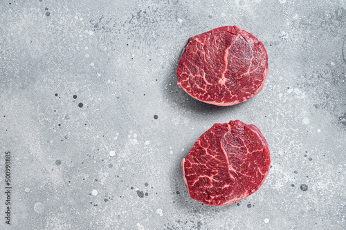 Raw fillet Mignon beef steaks on a butcher board. Gray background. Top view. Copy space