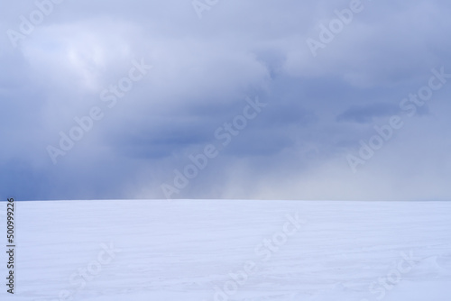 An impending snow cloud against the background of an endless snow-covered area. Copy space.