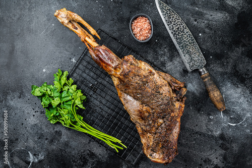 BBQ Roasted lamb mutton leg with herbs and spices on a grill. Black background. Top view