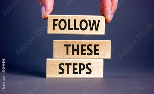 Follow these steps symbol. Concept words Follow these steps on wooden blocks. Businessman hand. Beautiful grey table grey background. Business and follow these steps concept. Copy space.