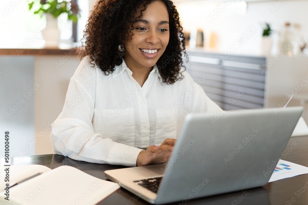 Confident african american businesswoman working on laptop at her workplace at modern home. Confident african american businesswoman working on laptop at her workplace at modern home.