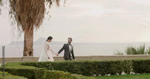 Young married couple walks on path in Isola Del Garda side view..