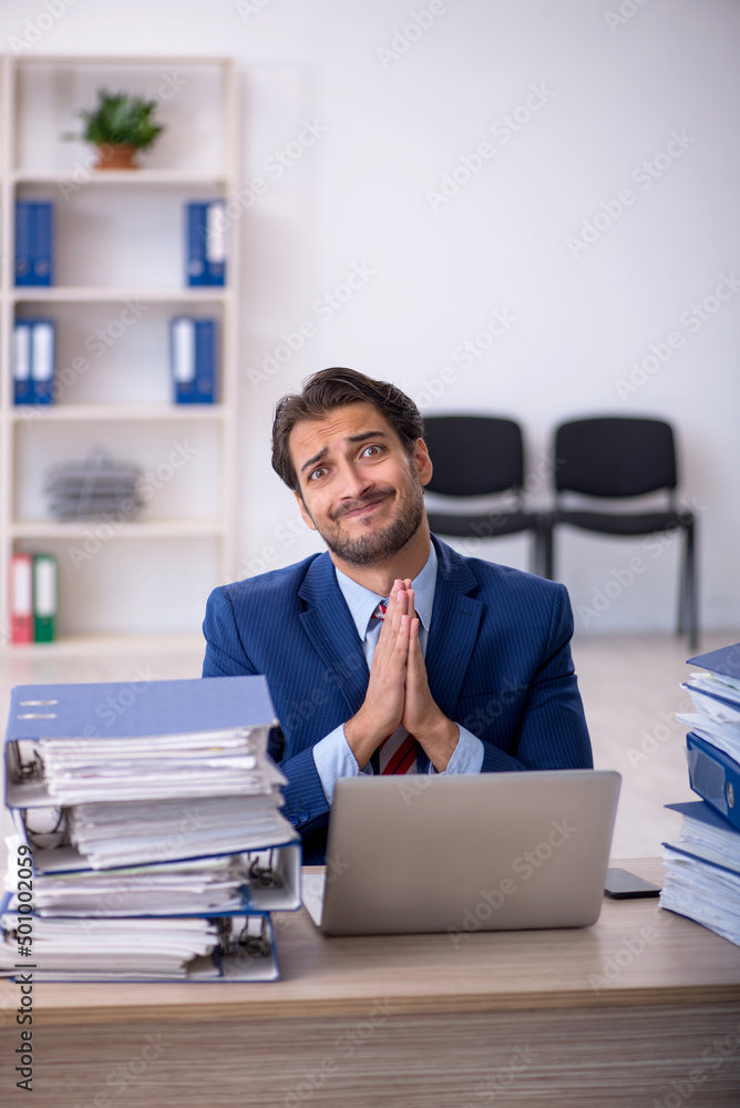 Young male employee and too much work in the office Young male employee and too much work in the office