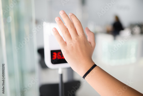 Closeup hand of child test a body heat at the temperature meter stand in front of the cafe
